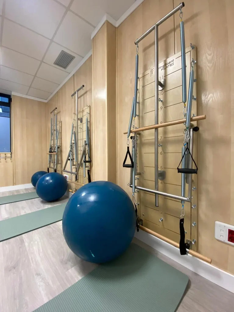 Sala de pilates terapéutico con barras de pared y balón de ejercicio.