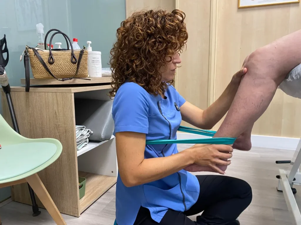 Ejercicio de rehabilitación con banda elástica y fisioterapeuta.