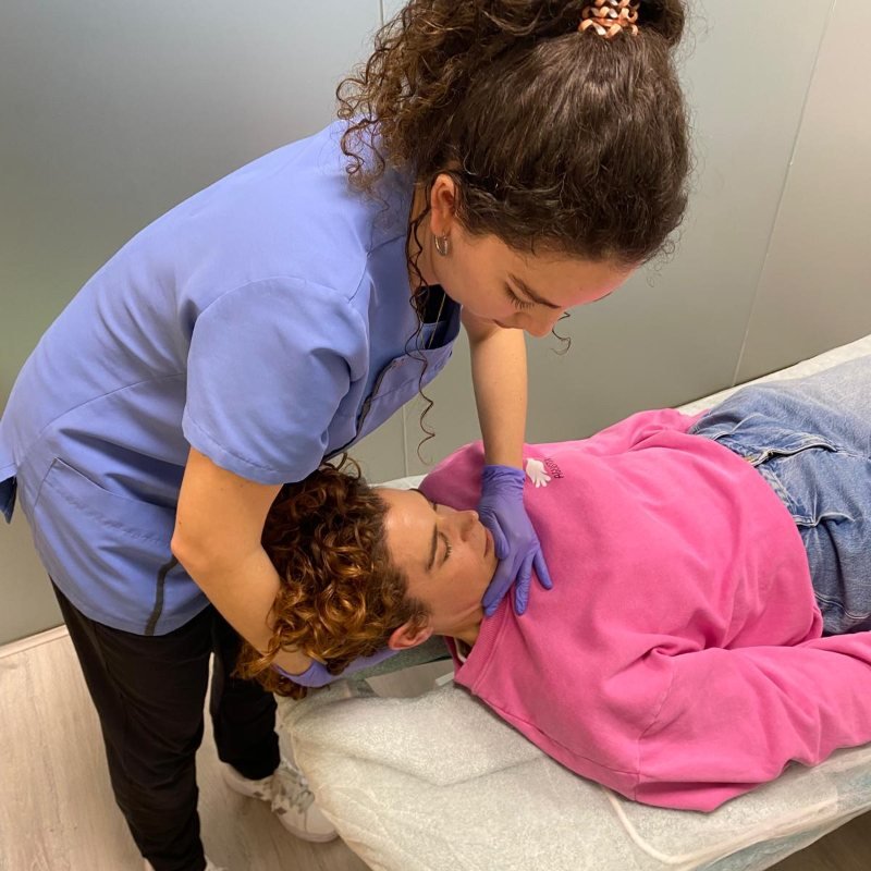 Tratamiento de la ATM en Punto Fisio, Ciudad Lineal Fisioterapeuta colegiada de Punto Fisio tratando la articulación temporomandibular de una paciente tumbada en la camilla, en Ciudad Lineal